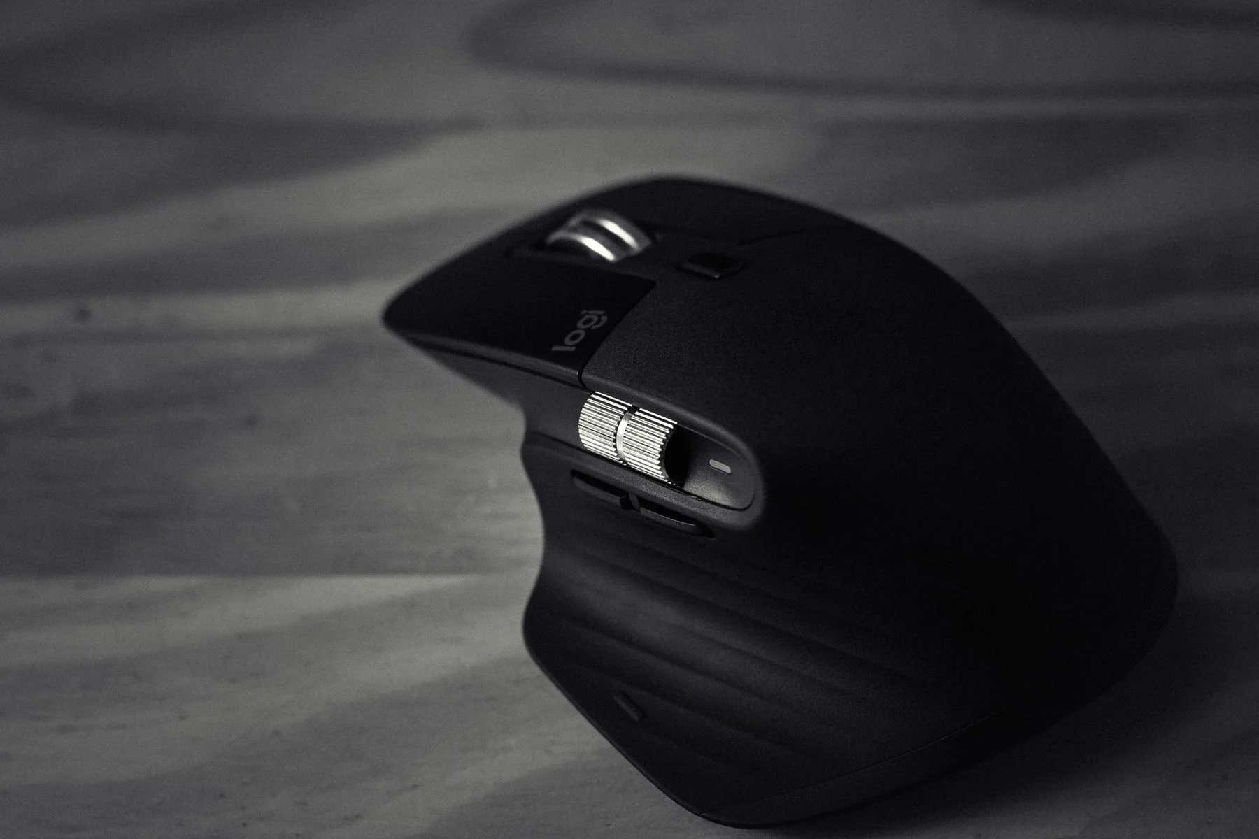 A black computer mouse on a wooden surface